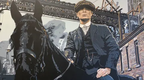 Sue Verity Art A painting of Tommy Shelby from Peaky Blinders, a man in a hat and 1920s style clothing is on top of a black horse