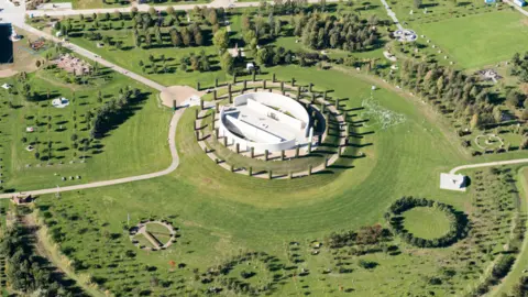 Getty Images An aerial view of the National Memorial Arboretum with the large circular white main memorial in the centre with smaller gardens and memorials around it.