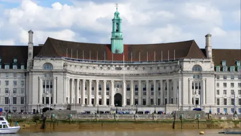 Getty Images Front of London County Hall, a large building with columns with the River Thames running in front of it