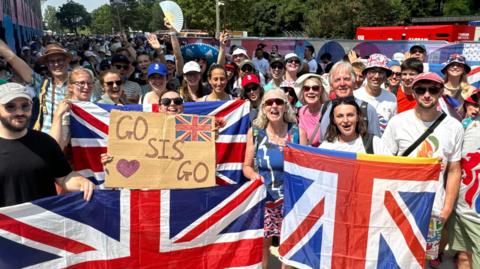 Dozens of people holding Union flags and celebrating Emily Craig and Imogen Grant's Gold medal in Paris