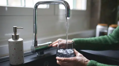 Getty Images A glass is held under and tap in a kitchen and is being filled with water