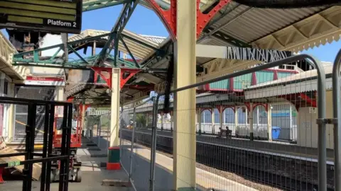 A rail station showing a damaged roof from inside