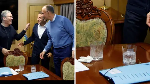 A composite image of British Prime Minister Keir Starker, French President Emmanuel Macron and German Chancellor Friedrich Marx greeting each other around a table. The left side of the image shows the three leaders smiling and reaching for each other, standing around a mahogany table inside a large train carriage. On the table are glasses of water, a tissue, a wooden cocktail stick and packs of paperwork in blue binders. The right side of the image is a closer view of the same photo, zooming in on the tissue and wooden cocktail stick.