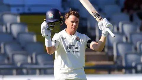 Marcus Harris raising his bat after scoring a century for Lancashire