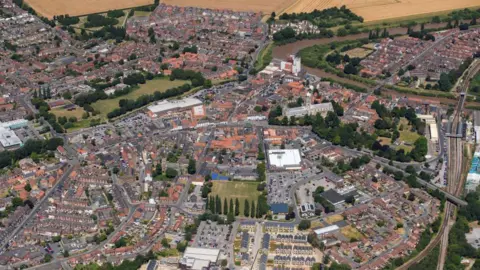 A drone shot of Selby in North Yorkshire, showing a mass of houses, greenery, and the railway.