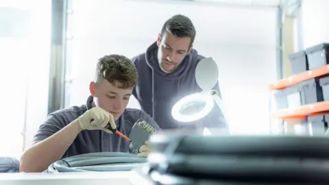 Apprentice and electrical engineer mentor in cable finishing factory - stock photo.