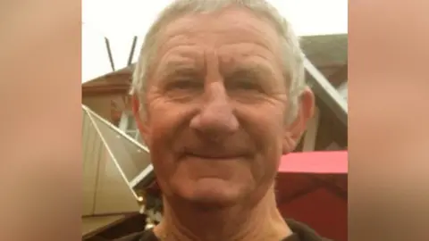 A man with grey hair smiling at the camera.