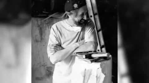 Joseph Mason Paul Mason resting on an unfinished sculpture, with tools next to him