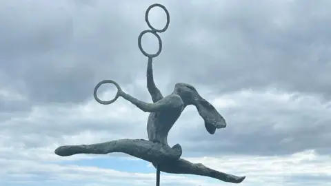 Lyme Regis Town Council A statue of a hare leaping in the air whilst doing the splits and juggling three things