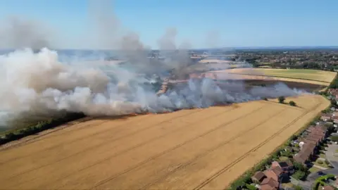 A drone shot of smoke rising from a farm field.