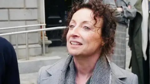 Trudi Walsh speaking outside court, she has dark hair and is wearing a grey jacket and scarf.