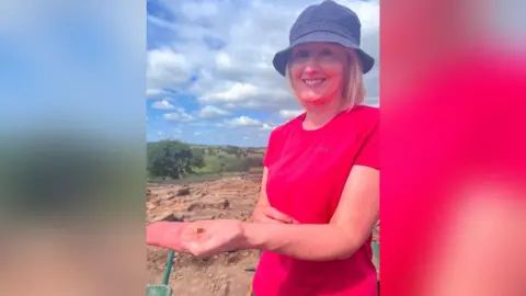 The Vindolanda Trust Sue Mingay holds a small bone die in the palm of her hand at the Magna trench excavation in Northumberland.