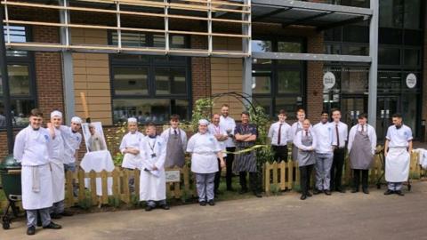 City College Southampton students stood in chefs' attire outside the college ready to cut the ribbon on the garden