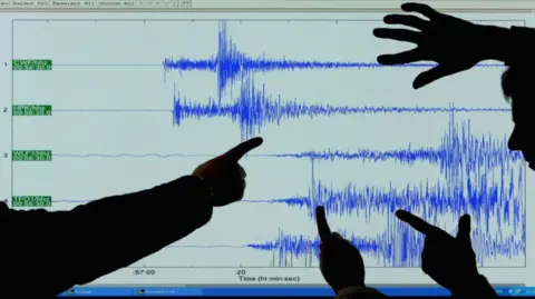 British Geological Survey scientists look at a seismogram of an earthquake (file image from 2008)