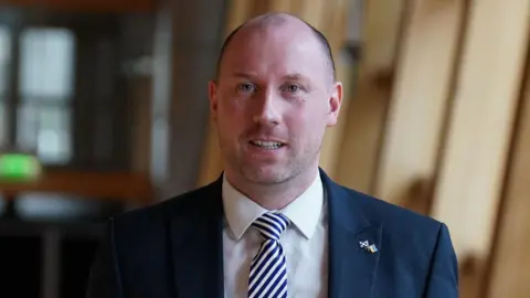 PA Media Neil Gray headshot in a wooden corridor at scottish parliament