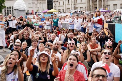 Female football fans wearing England shirts watch the football
