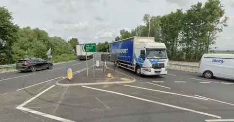A dual carriageway as it joins a roundabout. there is a green sign saying A47 King's Lynn / Wisbech