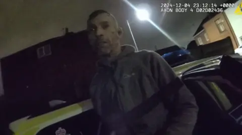 GMP Police bodycam footage of Draper, with two blood marks on his face and wearing a hoodie, being arrested outside his home in the dark