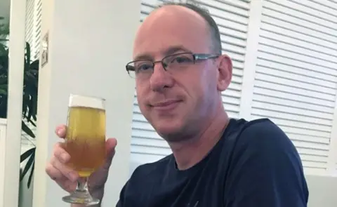 Nottinghamshire Police A man in glasses and dark shirt holding a beer.