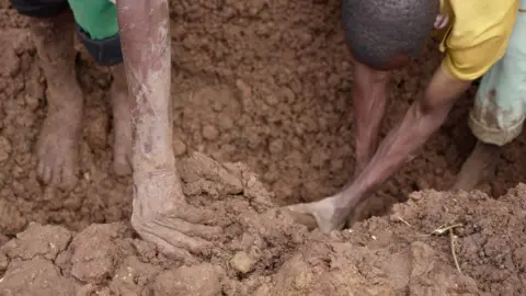 Amnessa Eva/BBC Mãos cavando na lama