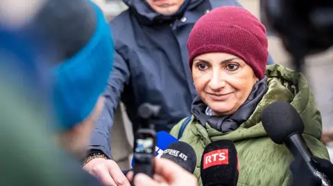 Getty Images A mother whose two daughters were injured in the fire, speaks to the press as she arrives for a hearing at the Office of the public prosecutor of the Canton of Valais as part of the inquiry into a devastating New Year's fire, in Sion on February 11, 2026