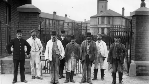 Topical Press Agency/Getty Images A black and white picture showing a group of men stand outside the Horton Asylum