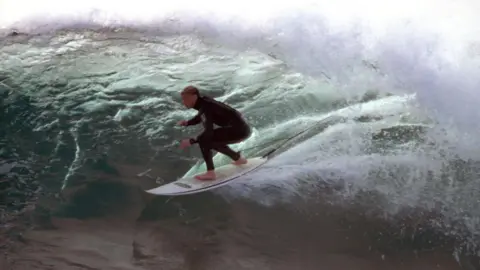 Carl Prechezer/FilmFour A male surfer riding a wave