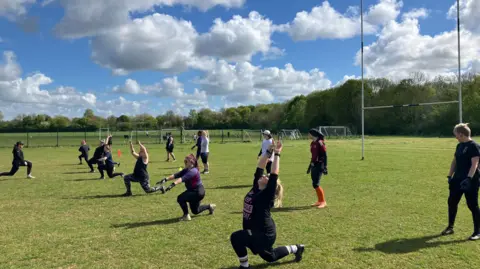Shariqua Ahmed/BBC Women training and doing exercise on the grass.