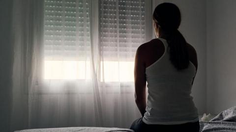 Silhouette of a woman staring out of a window