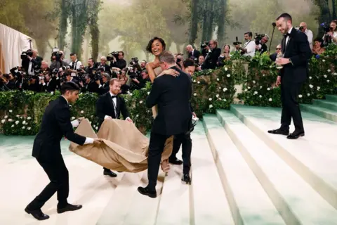 Taylor Hill/Getty Images Tyla is carried up the Met Gala stairs by publicists