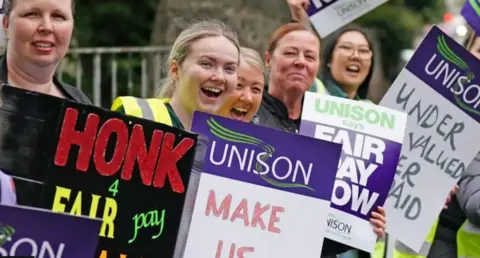 A group of striking workers with placards on a picket line