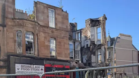 A collapsed building with some storefronts