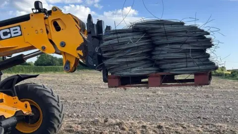 Sue Tyler-Moore A telehandler is photographed loading up some of the coils of wire donated from Whitehouse Farm Cherries.