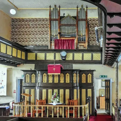 Weardale Museum The chapel is almost complete the walls have been painted yellow and wood carvings decorate the space. An organ sits on the balcony.