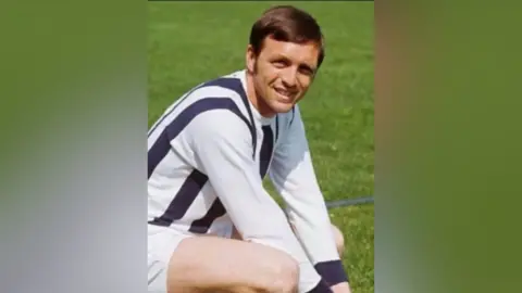 Supplied A young Jeff Astle looking directly at the camera and smiling, he is crouched down on the ground and dressed in his football kit.  