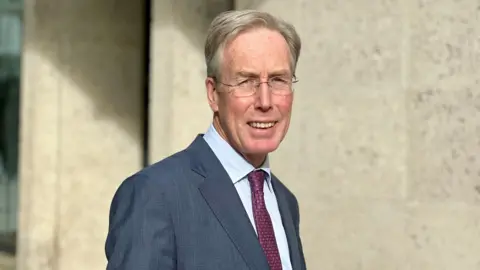 BRANWEN JEFFREYS/BBC A picture of Sir David Behan, the OfS chairman, in a navy suit with dark purple tie. He's looking and smiling at the camera.