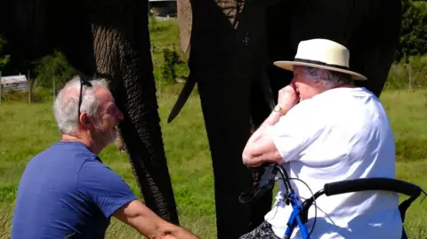 Margueriet Jones/Peter Haygarth Peter looks at his mother Beryl, who appears overcome with emotion being so close to an elephant. There are two elephants standing just beyond the pair.