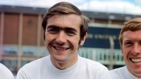 PA Media Close up of Terry Cooper in a white shirt smiling at the camera. On the right of the image is another man smiling.