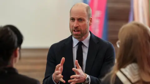 Reuters The Prince of Wales speaking to two people while gesturing with his hands