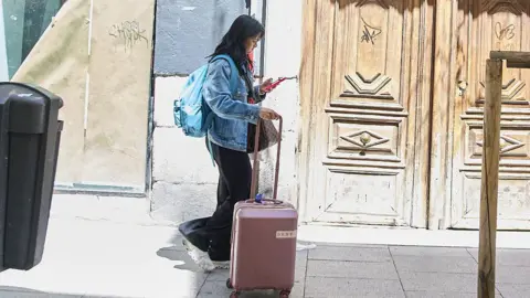 Getty Images A woman with a suitcase approaches an address in Madrid