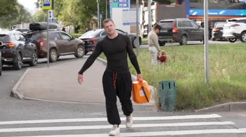 Man walks away from petrol station carrying a jerrycan