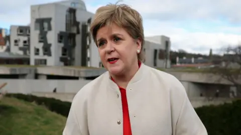 Nicola Sturgeon, who has short fair hair, speaks outside the Scottish Parliament. 