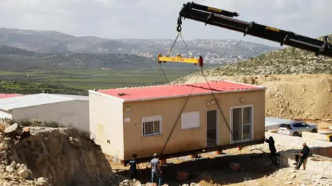 Reuters A crane lowers a caravan to the ground in the West Bank settlement of Amichai (file photo)