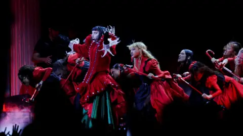 Reuters Lady Gaga dressed in red, surrounded by other performers, also in red, on stage at a free concert in Rio