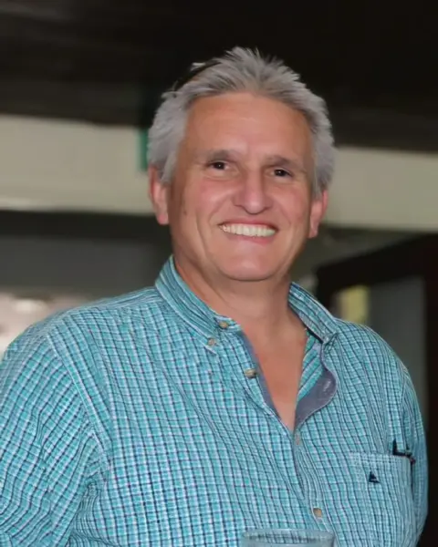 Charlotte Lunn A smiling man with silver hair and a light blue checked shirt.