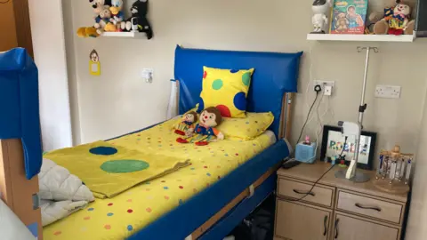 BBC News A new bedroom with a colourful bed with polka dot bedspread and a soft toys.