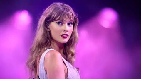 Getty Images Taylor Swift on stage at Wembley Stadium with a purple background