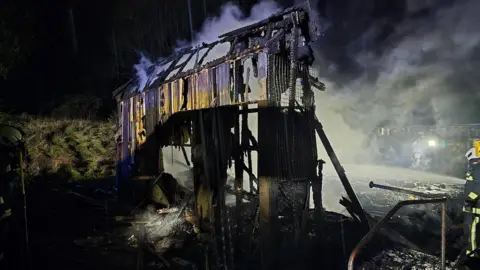 A picture of the building which had been majorly damaged in a fire. There is a wooden structure that has been damaged 