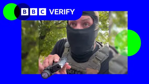 A masked ICE agents pointing a gun through a car window.