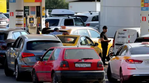 EPA Cars line up at a petrol station in Moscow on Thursday